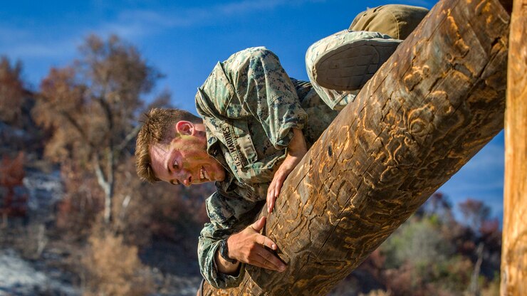 A marine climbs over a log.