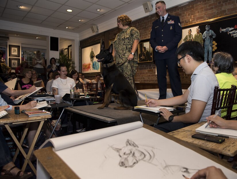 Master at Arms 2nd Class Ashlea Scully, 87th Security Forces Squadron military working dog handler, and U.S. Air Force Staff Sgt. Jeremy Callaghan, 87th SFS military working dog trainer, pose with K-9 Mmcgreevey during a sketch night at the Society of Illustrators Museum in New York, Aug. 30, 2018. Established in 1981, the society is the oldest nonprofit organization dedicated to the art of illustration in America and held the K-9 sketch night to promote a good relationship between military and the outside community.