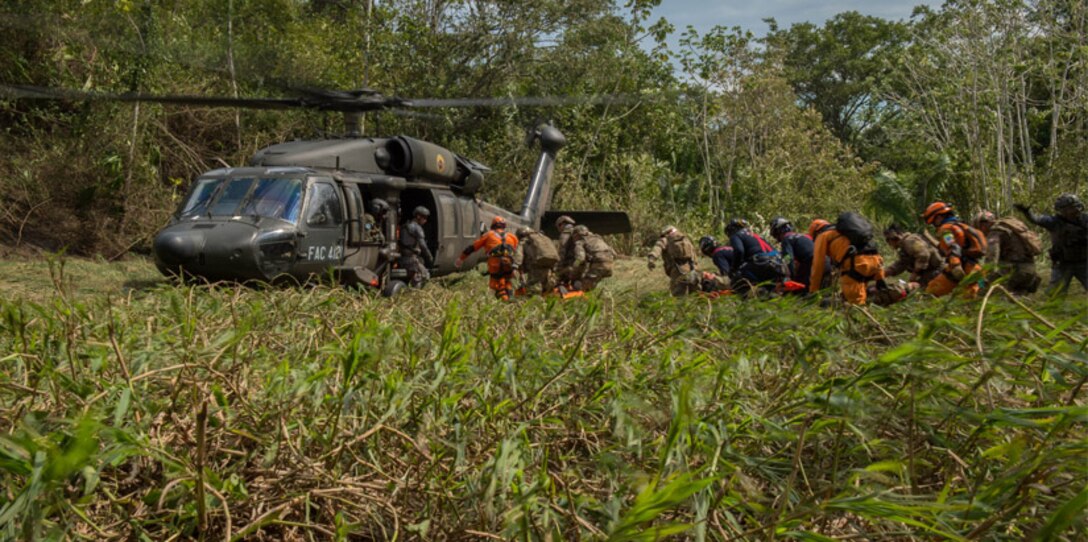 Colombian civil defense team, firefighters and Peruvian Airmen load triage patients onto a Colombian UH-60 Blackhawk