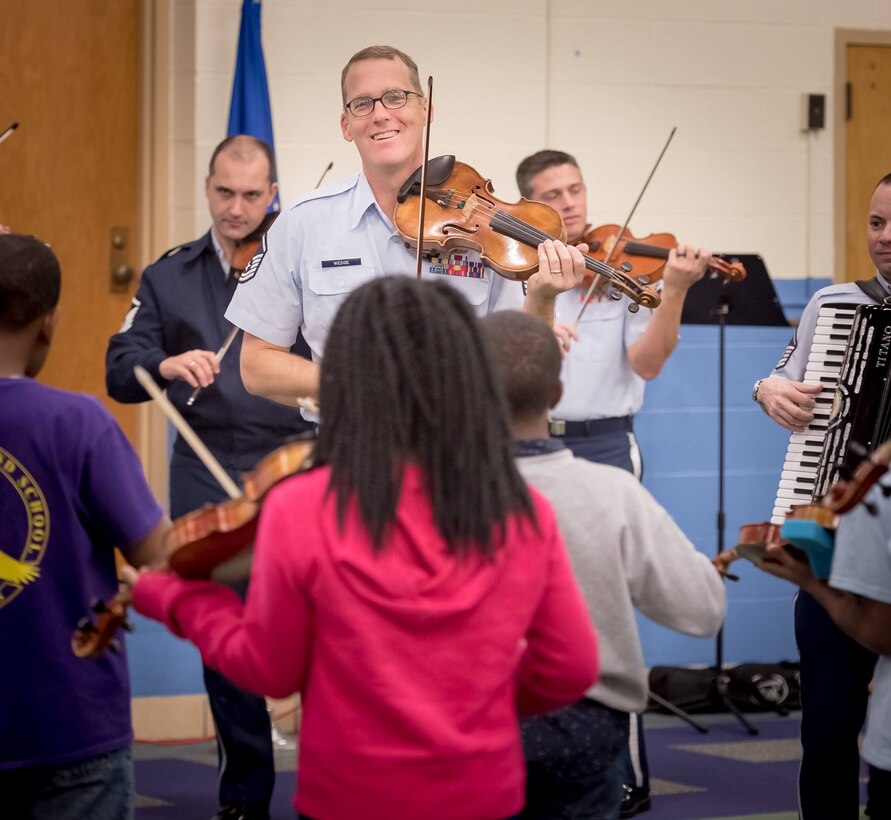 Master Sgt. Luke Wedge performs during a strings clinic at a local school