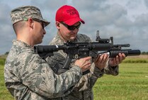 Staff Sgt. Nathan Minick, 375th Security Forces Squadron combat arms trainer, right, teaches a participant how to re-load a M203 40mm grenade launcher during the Non-Lethal Weapons Familiarization event Aug. 30, 2018, at the Illinois National Guard Training Area in Sparta, Illinois.