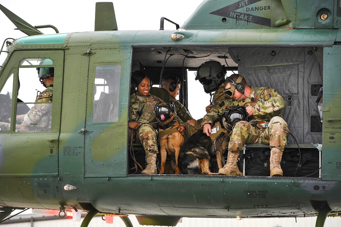 Airmen and their military working dogs take off in a UH-1N Iroquois helicopter during flight familiarization training.