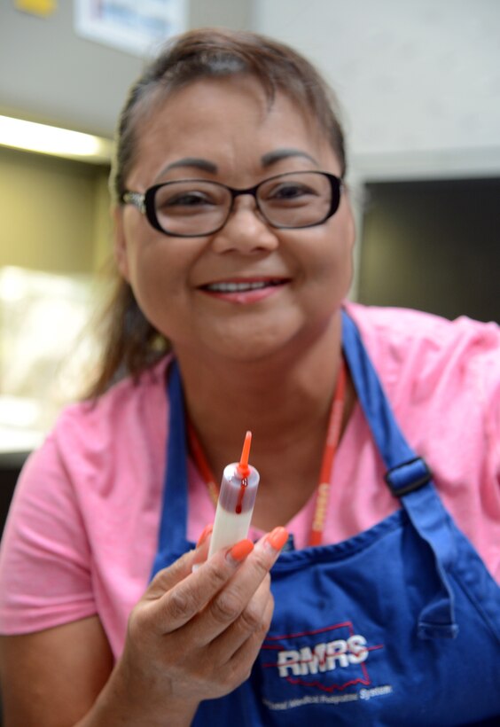 Sunny Schones, office manager for the women’s health and pediatric clinic at Tinker AFB, holds up a tool for applying fake blood makeup for an active shooter training Aug.15 in Bldg. 1094 at Tinker Air Force Base. (U.S. Air Force photos/Kelly White)