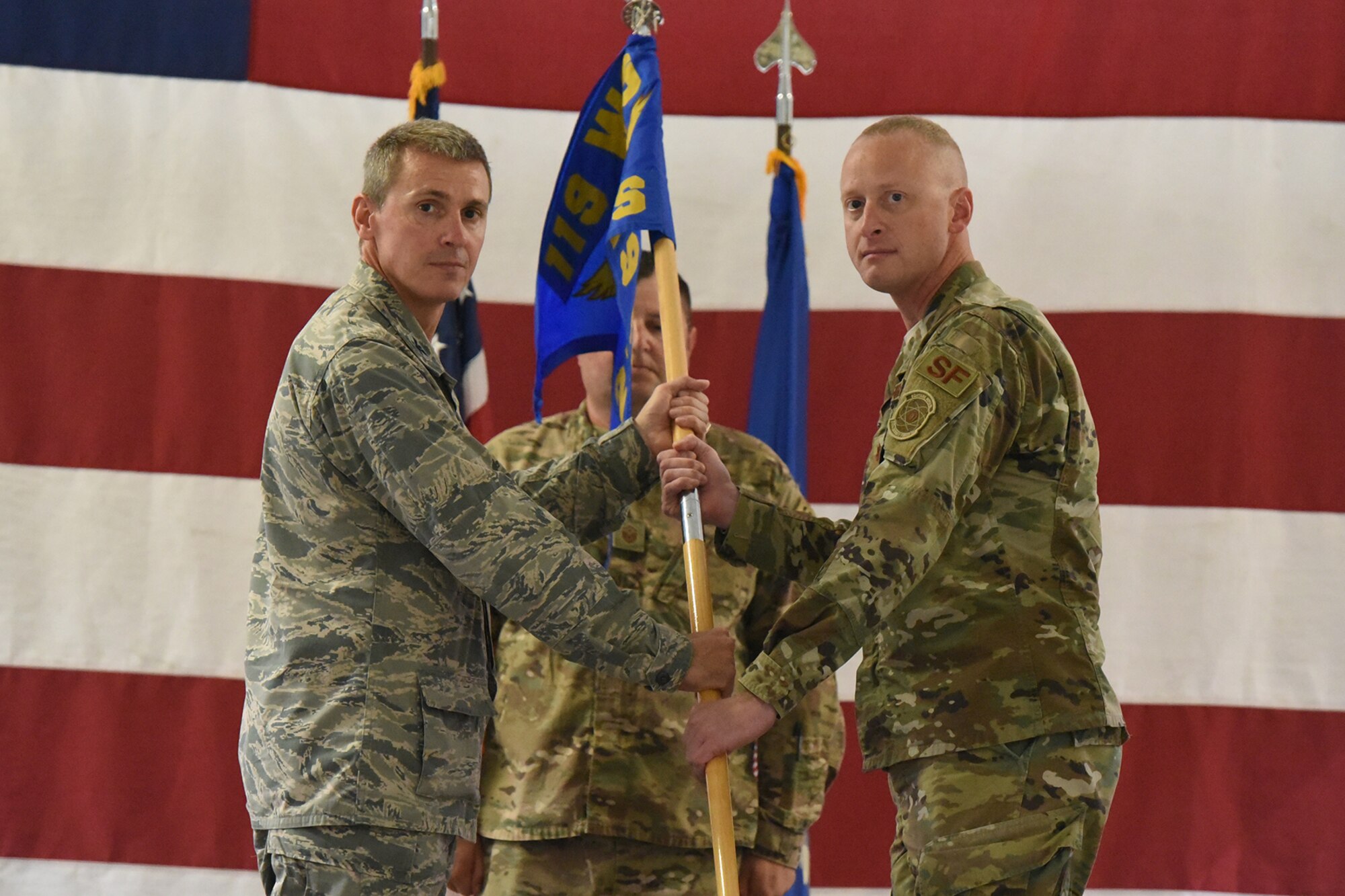 Col. Darrin Anderson, the 119th Wing commander, left, presents the 219th Security Forces Squadron unit flag guidon to Maj. Greg Goodman as Goodman assumes command in a symbolic gesture with the flag representing the squadron command of the 219th Security Forces Squadron at the Minot Air Force Base, N.D., Sept. 8, 2018.