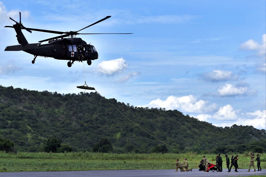 U.S. soldiers and Royal Thai army rangers load a Skedco litter into a helicopter.