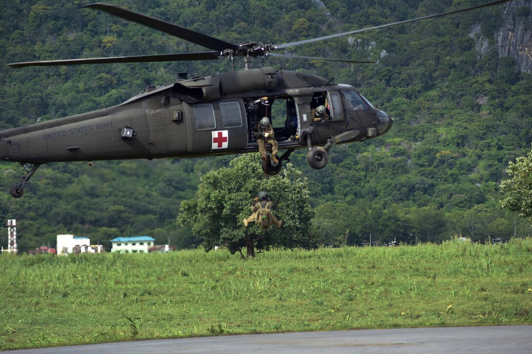 A soldier is lowered to the ground using the helicopters hoist system.