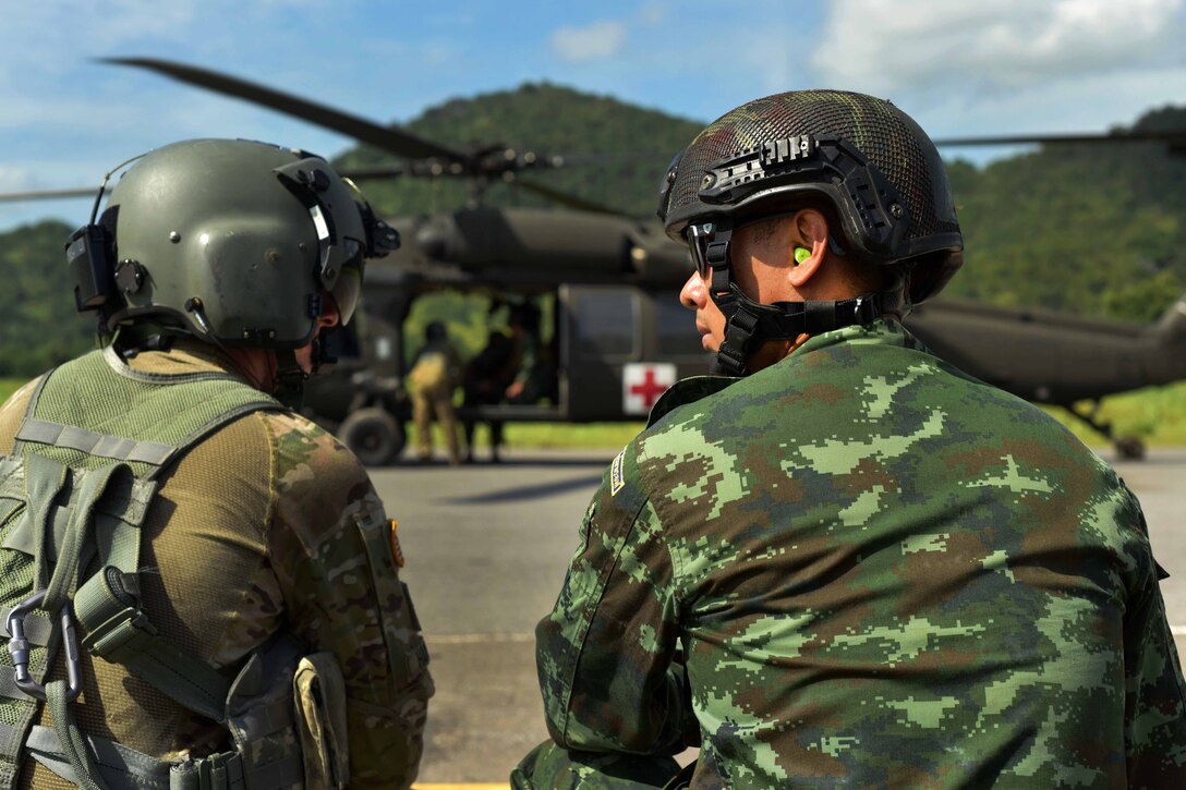 A soldier and Thai ranger talk training techniques before air medical evacuation training.