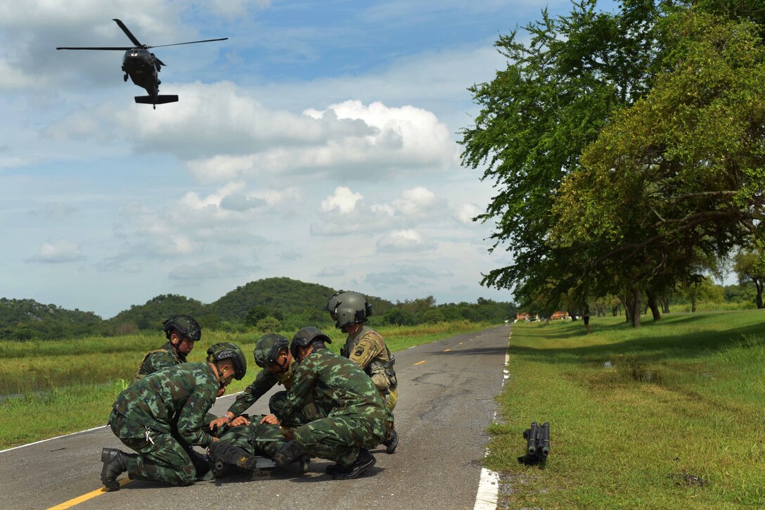 A soldier and Thai rangers wait for an approaching helicopter to land during air medical evacuation training.