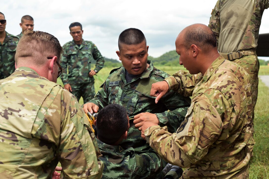 A soldier explains how to properly load a patient onto a helicopter’s jungle penetrator to Royal Thai army rangers.