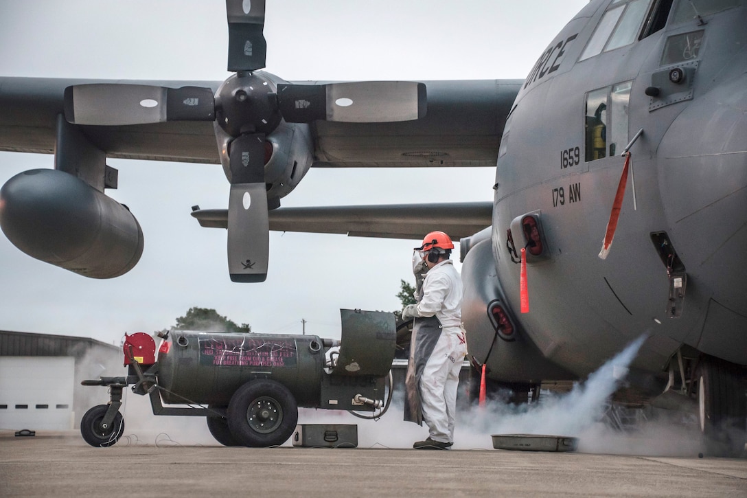 An airman refills the liquid oxygen tank in an aircraft.