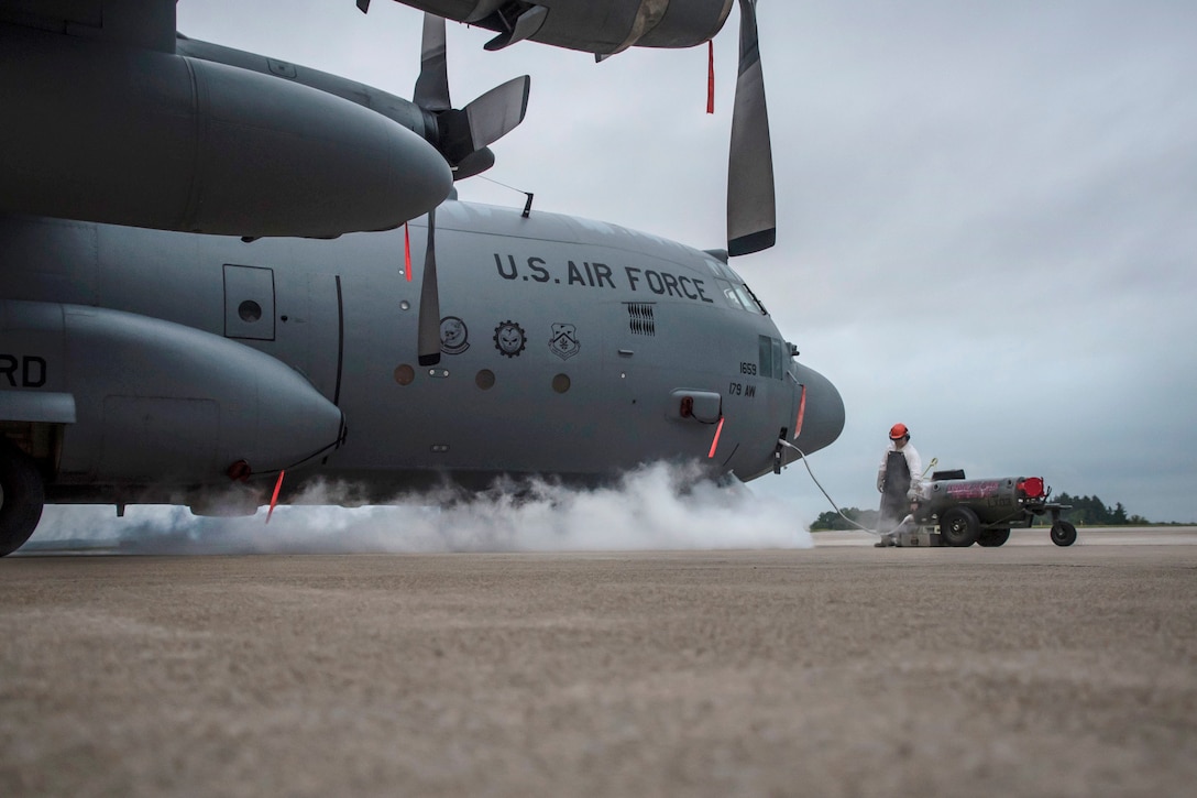 An airman monitors a control valve as an aircraft is being refilled with liquid oxygen.