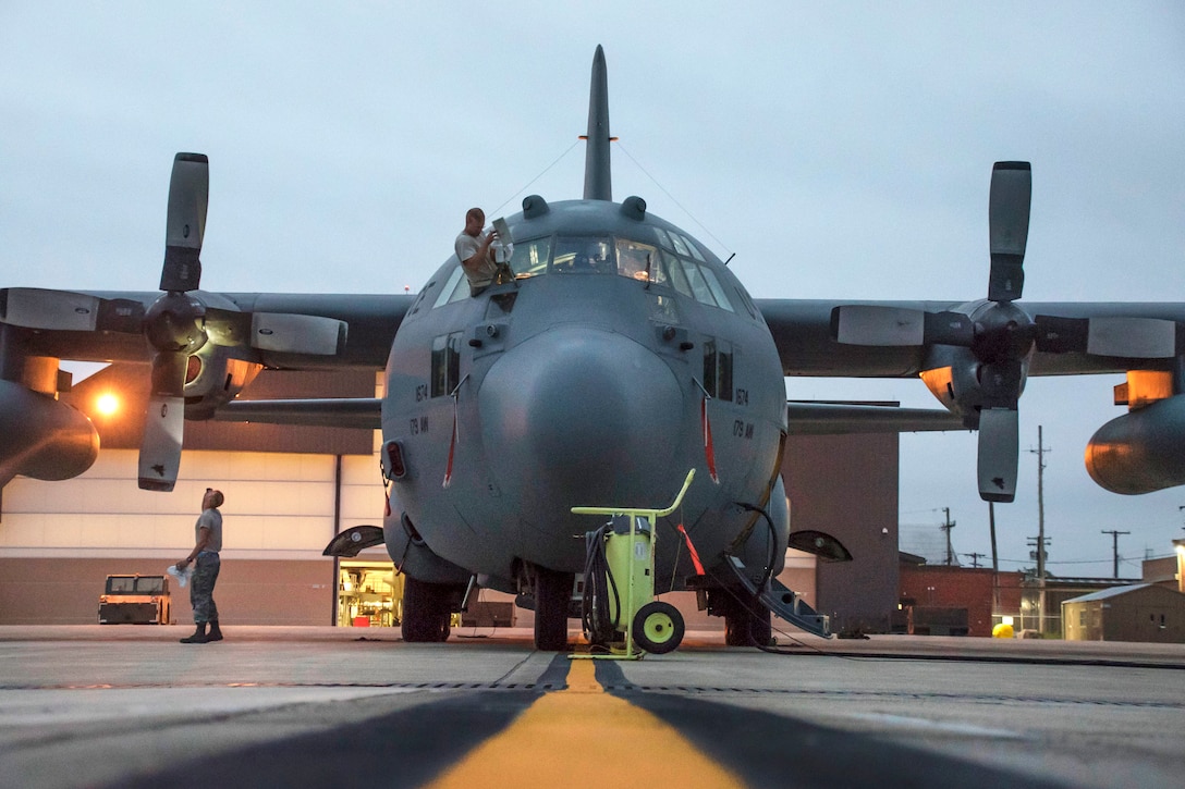 Airmen clean windows and check the propellers during daily routine preflight operation.