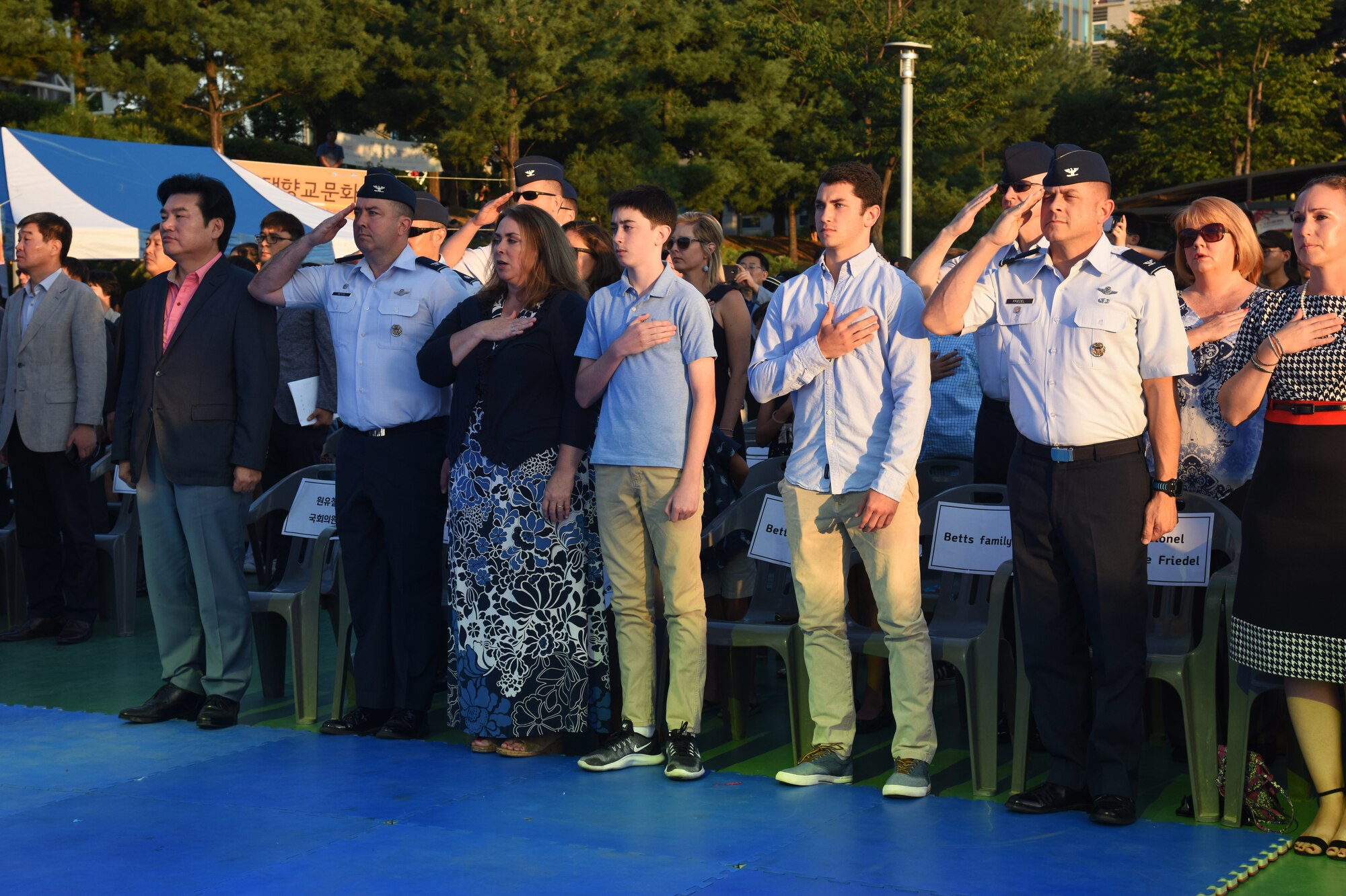 From left, National Assembly Of South Korea member Won Yoo Chul, U.S. Air Force Col. William Betts, 51st Fighter Wing commander and his family, and Col. Jesse Friedel, 51 FW vice commander and his family, pay respects to the U.S. flag during the playing of the American National Anthem before the start of the 15th annual Korean-American Friendship Cultural Festival at the Songtan Entertainment District, Republic of Korea, Sept. 8, 2018. The two-day event was held to help both cultures learn about each other and reinforce U.S. and ROK bond. (U.S. Air Force photo by Tech Sgt. Ashley Tyler)
