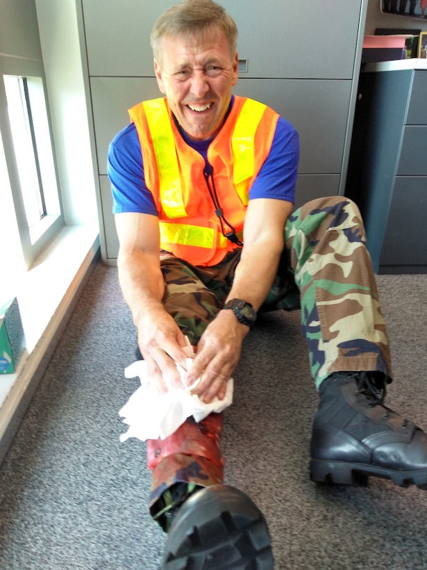 Man seated on floor, holding bandage to bloody leg