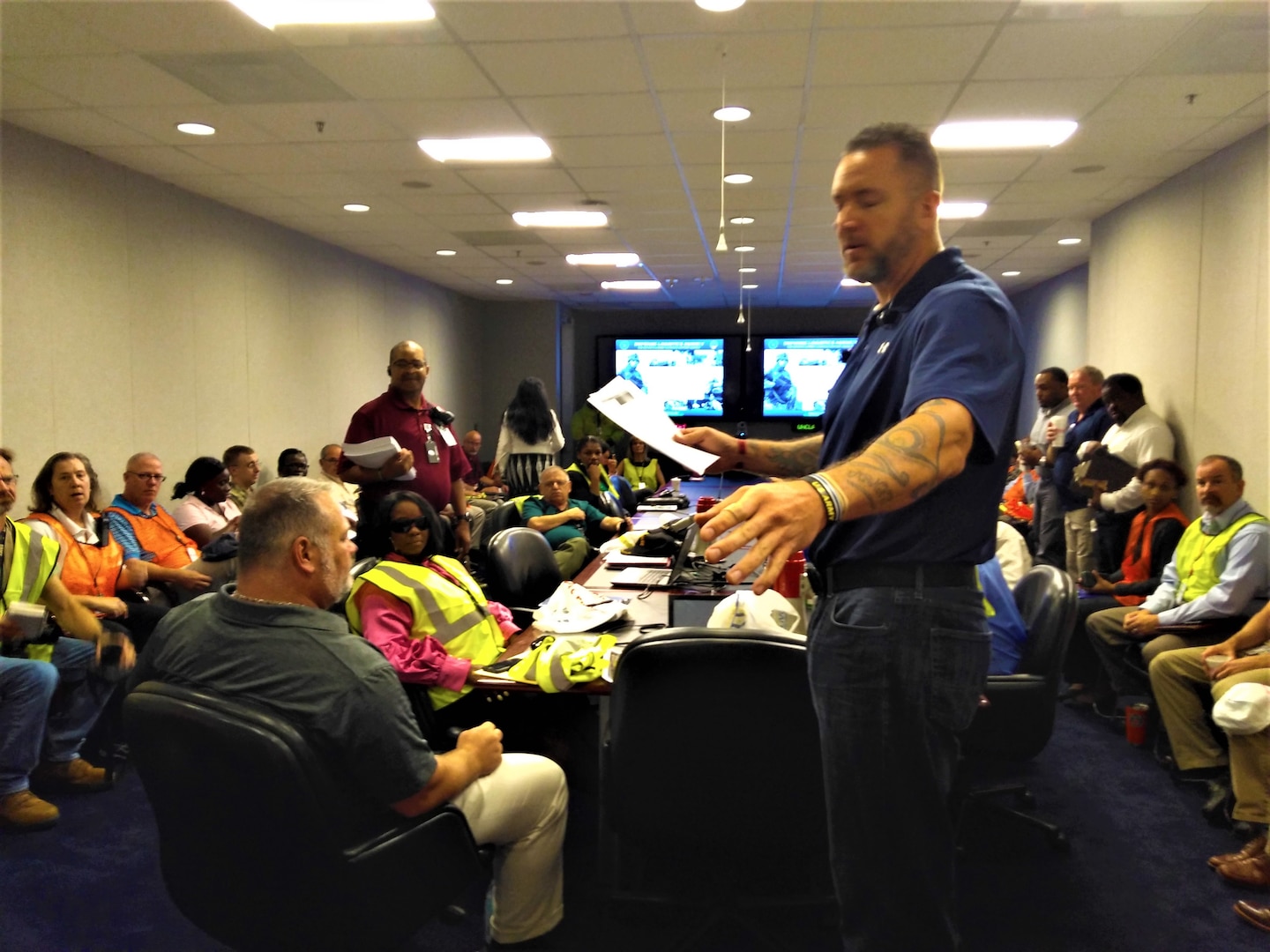 Man standing in conference room, gesturing, with others seated