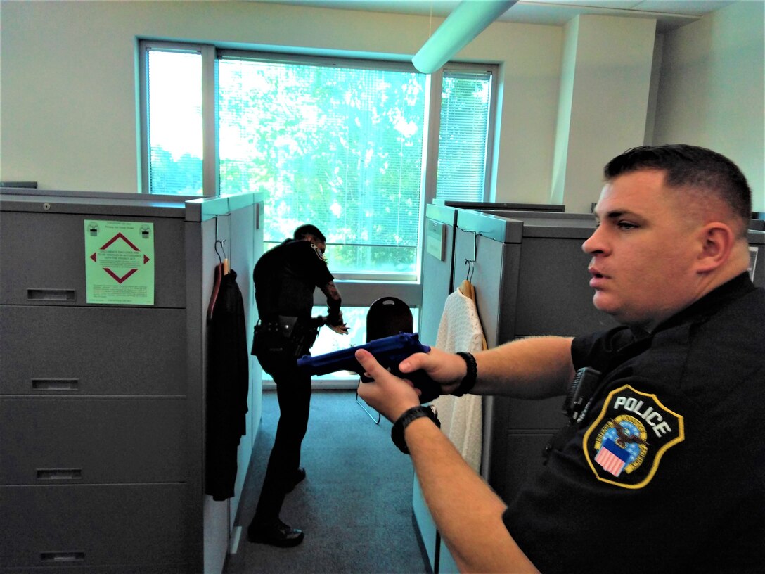 Police officers with mock guns drawn in office suite