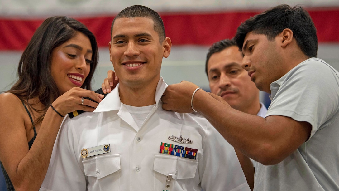 Family members place shoulder boards on a sailor.