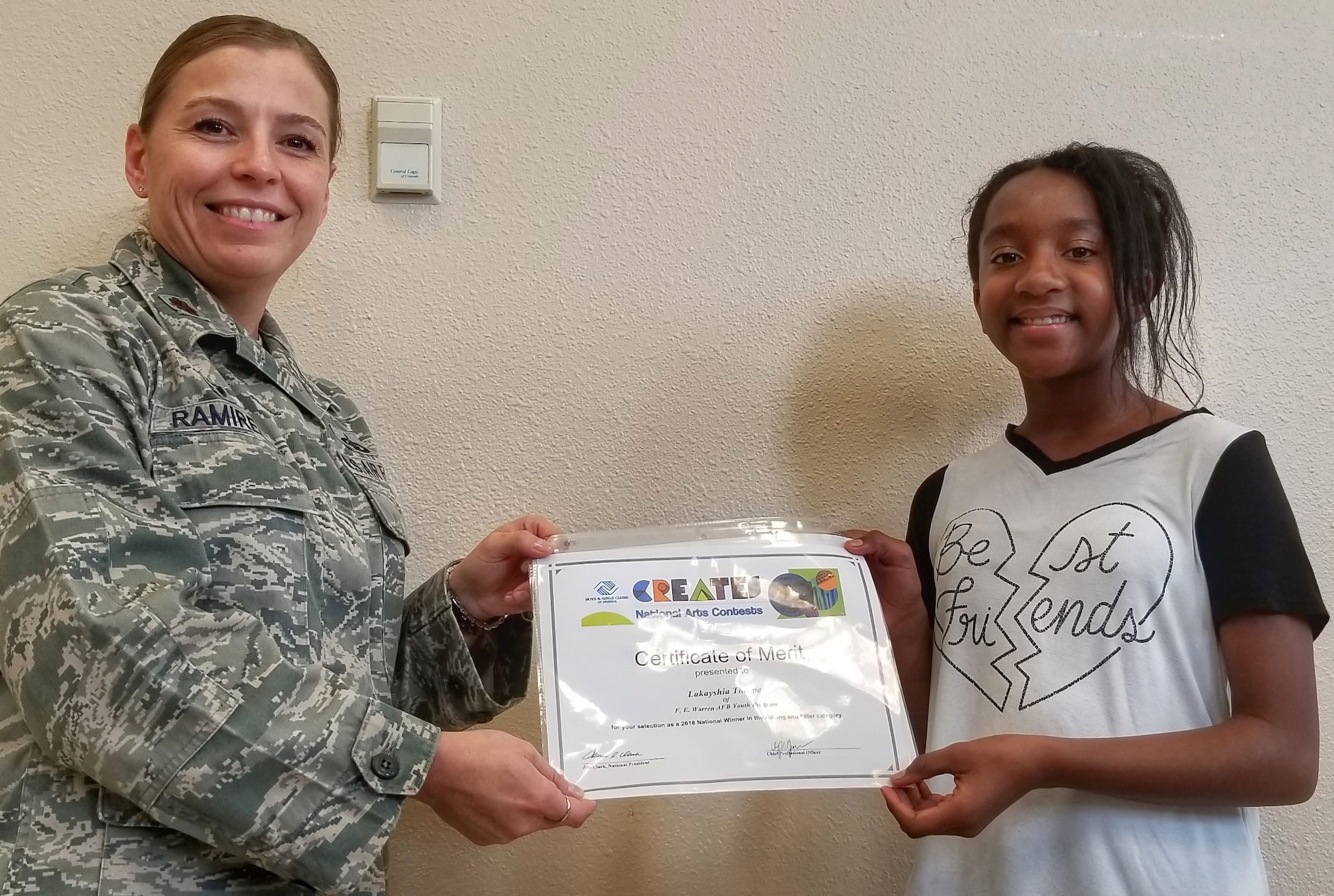 Maj. Isabella Ramirez, 90th Force Support Squadron commander, recognizes Lakayshia Thorpe, youth programs child, as the Boys & Girls Clubs of America 2018 National Arts Contest award winner for Photography, Editing and Filter Category at the F.E. Warren Air Force Base Youth Center Annex on Aug. 22, 2018. The competition's goal was to build confidence and empower youth in freedom of expression.  Thorpe’s artwork will travel to regional and national conferences across the country.