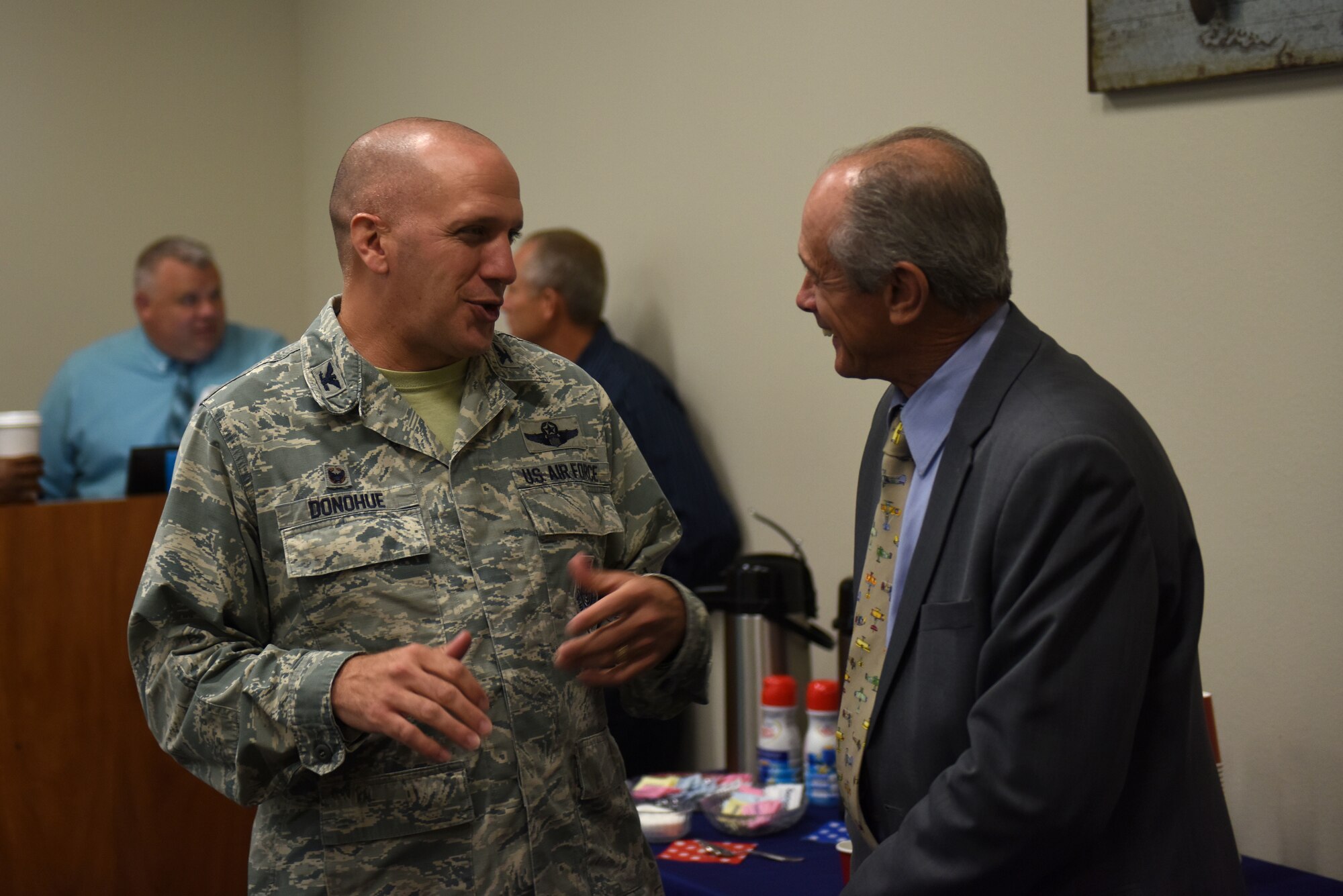 A man in the Airman Battle Uniform talks to a man in a suit.