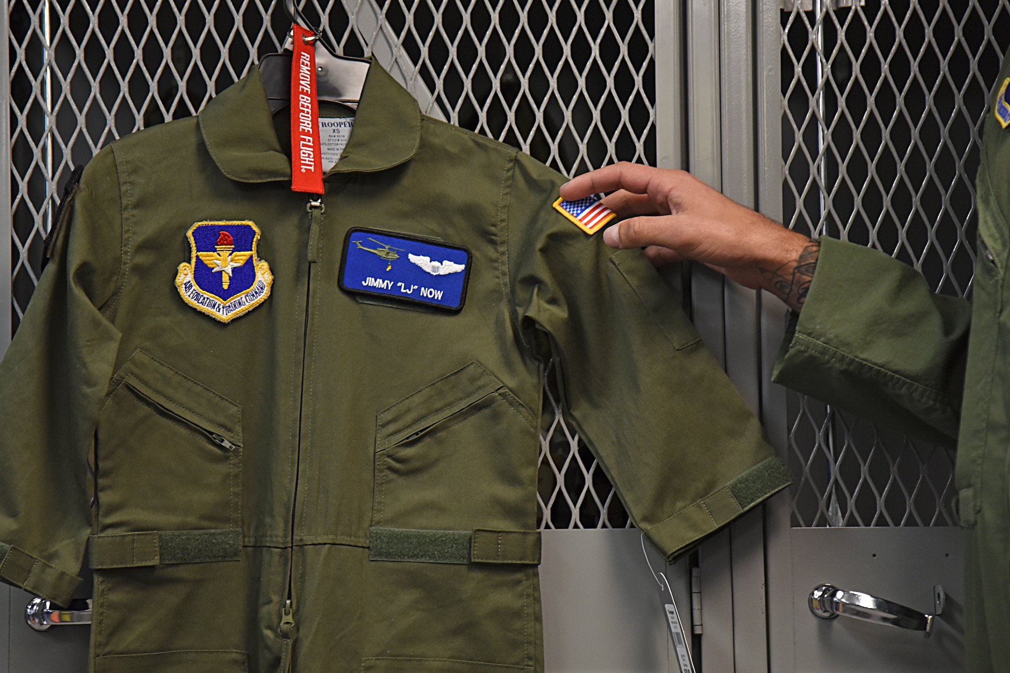Capt. Kyle Nelson, 36th Rescue Squadron standardization and evaluation chief, presents Jimmy "LJ" Now his own flight suit during the Now family's visit Sept. 7, 2018, at Fairchild Air Force Base, Washington. LJ also received a personalized helmet, plaque, helicopter joy stick and a homemade memory box to commemorate his time as a Honorary UH-1N Huey pilot. (U.S. Air Force photo/Staff Sgt. Mackenzie Mendez)