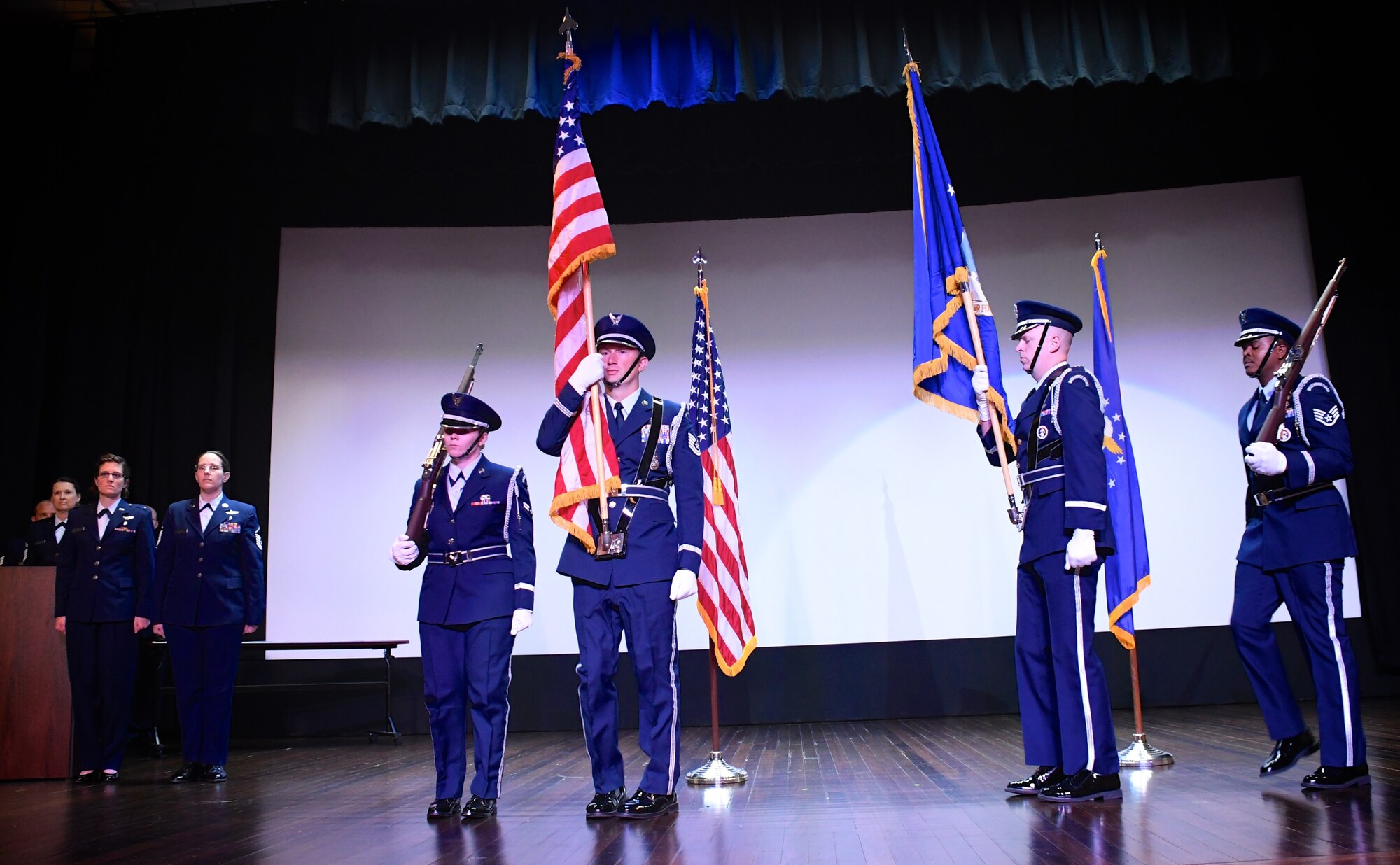 Members of the 932nd Airlift Wing Honor Guard bring the American flag and Air Force flag into the theater auditorium at the start of the unit's Non-Commisioned and Senior Non-Commissioned Officer Induction Ceremony held September 9, 2018, at Scott Air Force Base, Illinois.  Friends, family, and co-workers cheered as the new inductees walked up to collect their certificates from the commander of the wing, Col. Raymond Smith, and the 932nd AW Command Chief, Chief Master Sgt. Barbara Gilmore.  The event recognized the leadership and skills of those members achieving higher ranks and leadership expectation status recently.  (U.S. Air Force photo by Lt. Col. Stan Paregien)