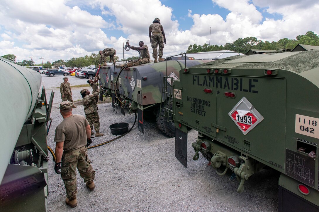 Soldiers transfer diesel fuel into tanker trucks.