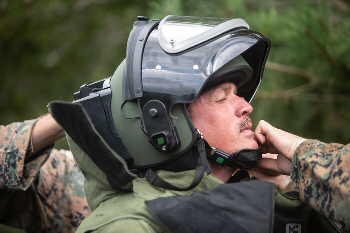 Sgt. Scott N. Schaller is assisted with fastening the helmet of his bomb suit Sept. 5, 2018 at Camp Fuji, Japan. Schaller uses the Explosive Ordnance Disposal bomb suit as protection while he inspects an improvised explosive device. EOD Company Marines validated proficiency and prepared for worldwide mission deployment in support of III Marine Expeditionary Force by testing their ability to disable and dispose of explosives. Schaller, a native of Easton, Pennsylvania, is an EOD technician with EOD Company, 9th Engineer Support Battalion, 3rd Marine Logistics Group. (U.S. Marine Corps photo by Lance Cpl. Armando Elizalde)