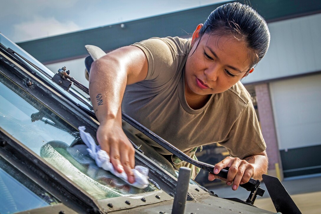 A soldier cleans the windows on a Black Hawk helicopter.