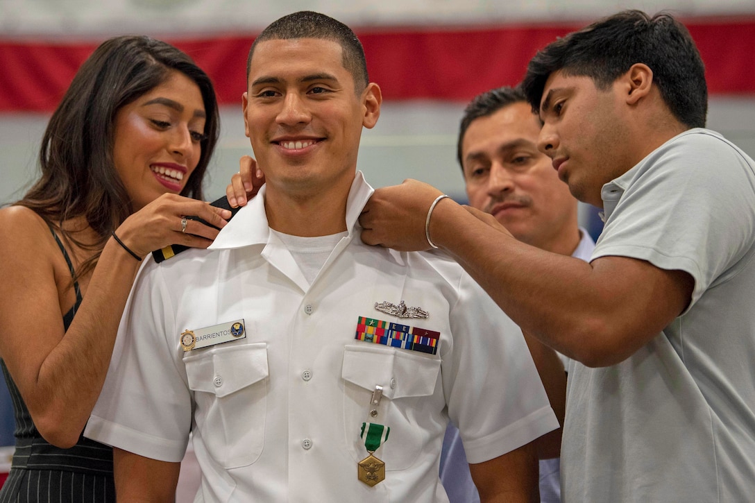 Family members place shoulder boards on a sailor.