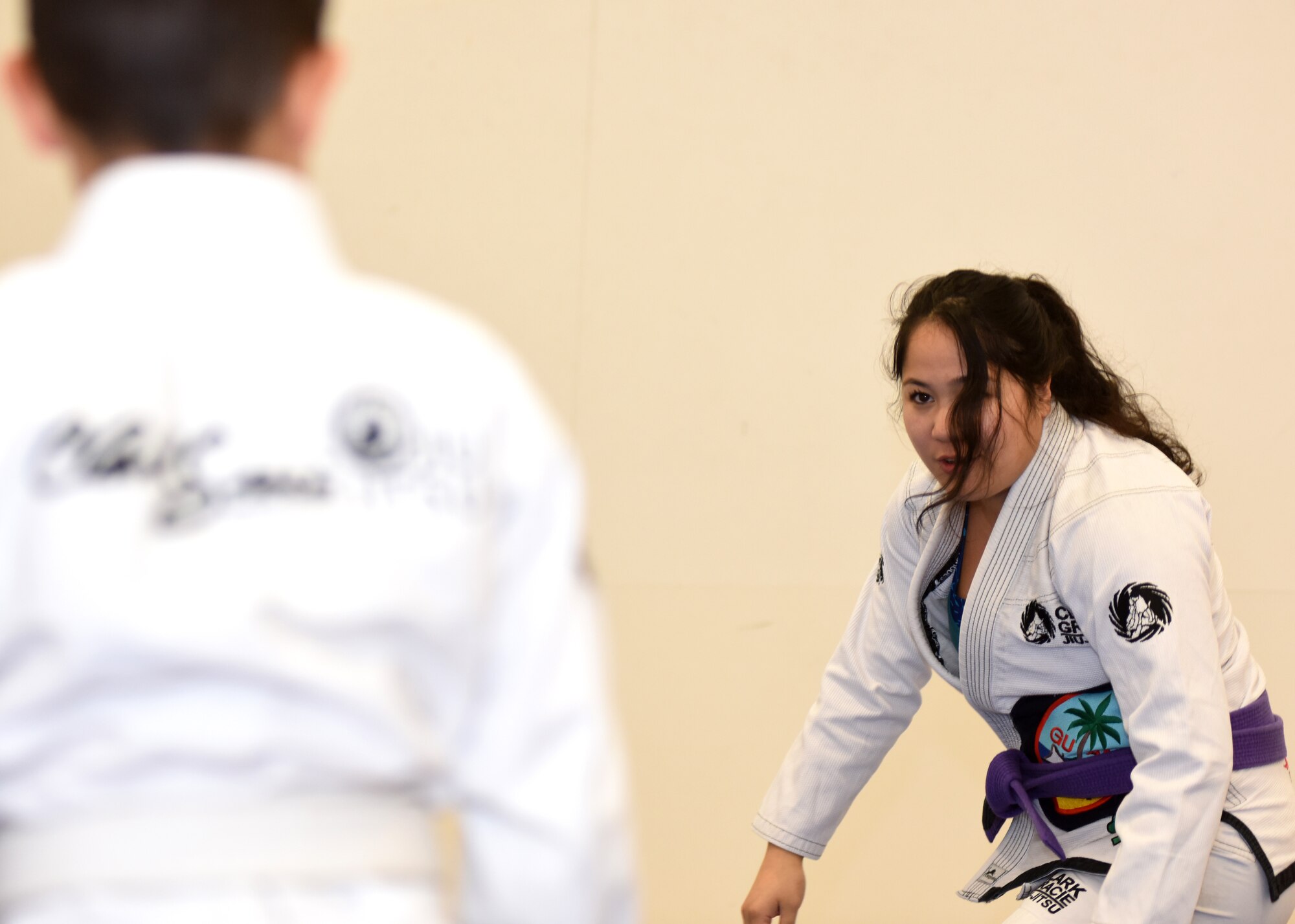 People in white uniforms practice martial arts on a  blue mat.