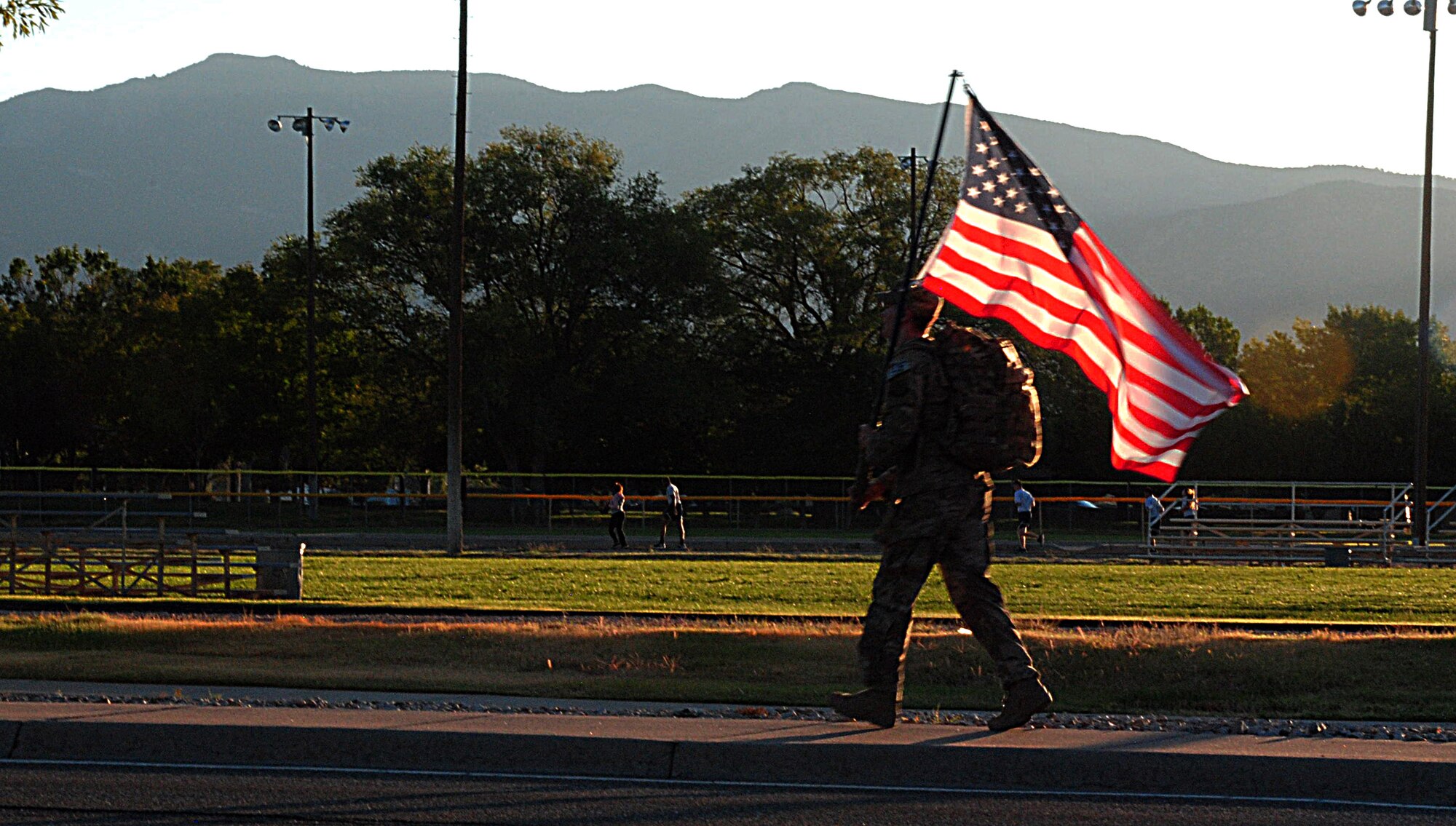 Senior Airman Samuel O'Brien with the 377th Special Forces Group carries the U.S. Flag during a ruck march commemorating the victims of the 9-11 attacks here. The march started at 6:46 a.m. (8:46 EDT, to mark the start time of when the first plane hit the twin towers 17 years ago. (U.S. Air Force photo by Jessie Perkins)