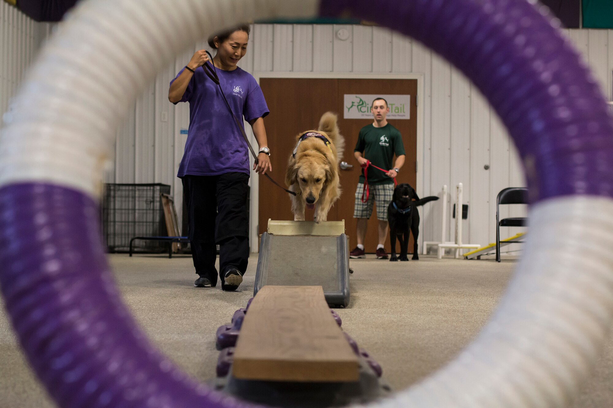 Chiaki Fanelli, a Circle Tail service dog trainer, and Palmer, a Circle Tail service dog, walk through an obstacle course at the indoor training center at Circle Tail, Inc. in Pleasant Plain, Ohio, August 16, 2018.