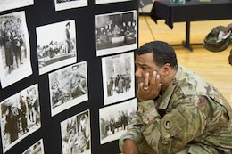 Fort Knox Ky. - Staff Sgt. Patrick Washington, senior disbursing analyst, 18th Financial Management Support Center, 1st Theater Sustainment Command, looks at a display of images from the Holocaust April 20, 2018 at the Sadowski Center at the 2018 Days of Remembrance Commemoration Program.