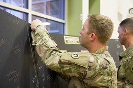Fort Knox Ky. - Staff Sgt. Scott Stahley, motorpool noncomissioned officer in charge, Headquarters and Headquarters Company, 1st Special Troops Battalion, 1st Theater Sustainment Command, signs a wall as a pledge to remember those who died in the Holocaust April 20 at the 2018 Days of Remembrance Commemoration Program.