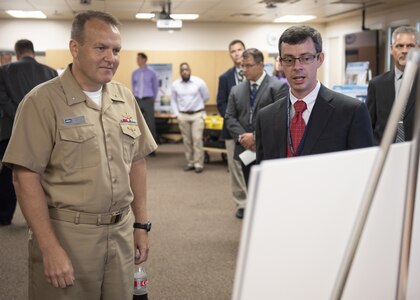 PANAMA CITY, Florida - Naval Surface Warfare Center Panama City Division (NSWC PCD) Multiple Vehicle Communications Systems Technical Direction Agent Lead Evan McCaw briefs Commander, NSWC Rear Adm. Tom Anderson, USN, about the Navy Innovative Science and Engineering Alternative Mission Packages project Sept 5, 2018. U.S. Navy photo by Ron Newsome