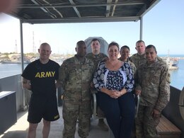 KUWAIT NAVAL BASE, Kuwait - – Theresa Scott, family readiness support assistant, 1st Theater Sustainment Command (TSC), middle, poses with several 1st TSC Soldiers while onboard an Army Landing Support Vessel, June 16. Scott traveled to Camp Arifjan to experience life as a Soldier on deployment.