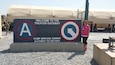 CAMP ARIFJAN, Kuwait – Theresa Scott, family readiness support assistant, 1st Theater Sustainment Command (TSC), stands in front of the 1st TSC Theater Gateway T-Wall, June 18. Scott traveled to Camp Arifjan to experience life as a Soldier on deployment.