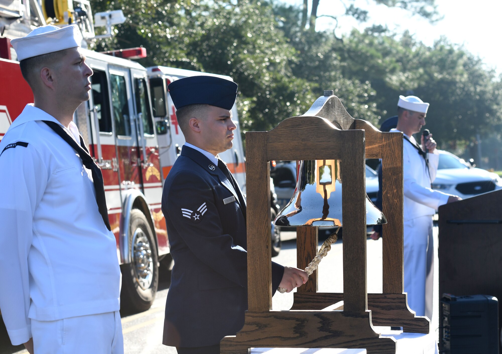 U.S. Air Force Senior Airman Zachary Slater, 81st Infrastructure Division firefighter, rings a tribute bell as Chief Aviation Electronics Technician (Select) Adrian Pineiro, The Center for Naval Aviation Technical Training Unit student, stands by during a 9/11 ceremony in front of the 81st Training Wing headquarters building at Keesler Air Force Base, Mississippi, Sept. 11, 2018. Seventeen years ago on Sept. 11, 2001, 19 terrorists simultaneously hijacked four passenger jets; flying one into the Pentagon and two into the World Trade Center in New York City, New York, and one crashing outside of Shanksville, Pennsylvania. A total of 2,996 people were killed in the attacks. (U.S. Air Force photo by Kemberly Groue)