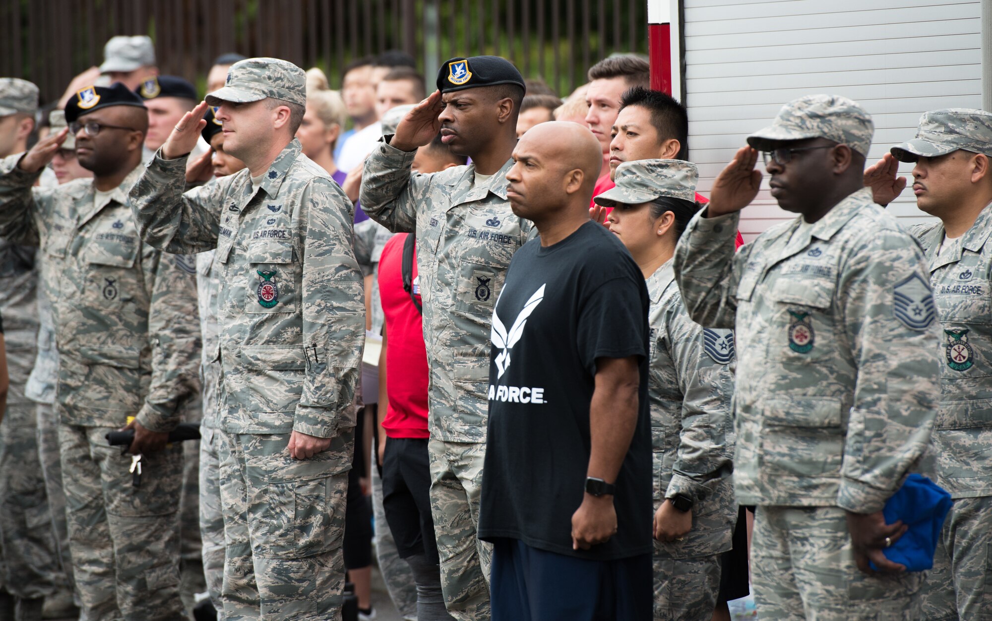 Yokota Air Base members salute during the playing of the Japanese and American National Anthems