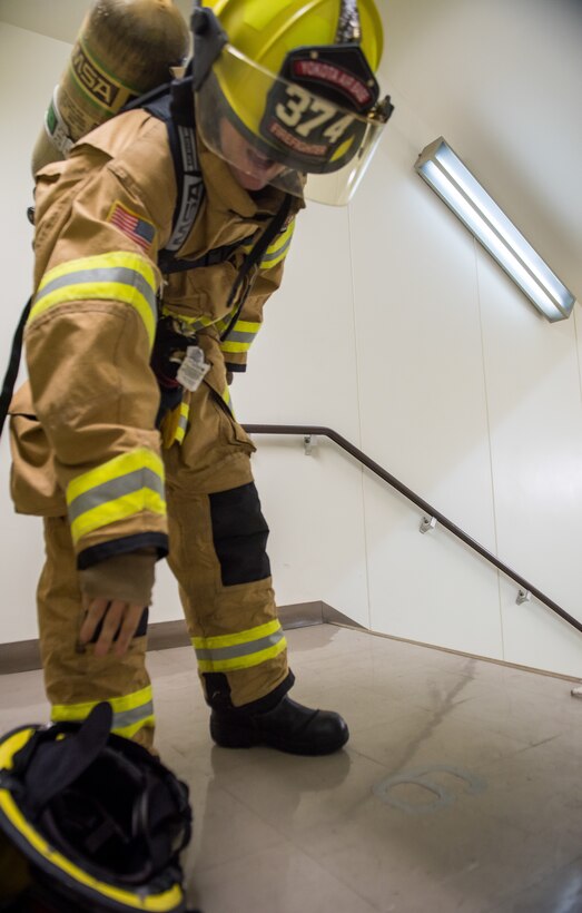 A 374th Civil Engineer Squadron firefighter releases a dog-tag into a fire fighter's helmet