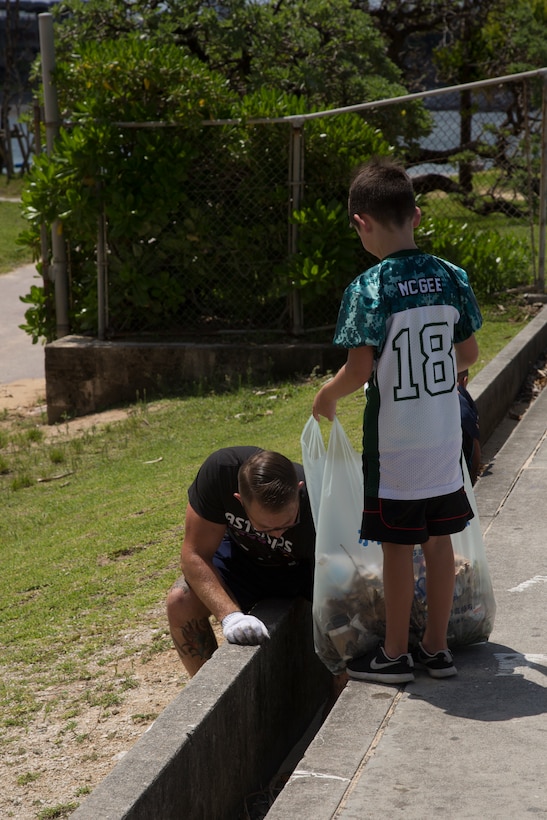 CHATAN, OKINAWA, Japan – Father and son collect trash during a friendship day beach cleanup Aug. 4 on the Sunset beach sea wall in Chatan, Okinawa, Japan.