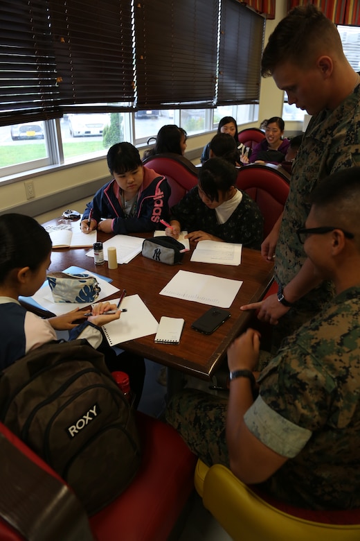 CAMP COURTNEY, OKINAWA, Japan – Students from the local community work on homework with Marines during Camp Courtney’s Summer English class Aug. 16 at the Camp Courtney Mess Hall, Okinawa, Japan.
