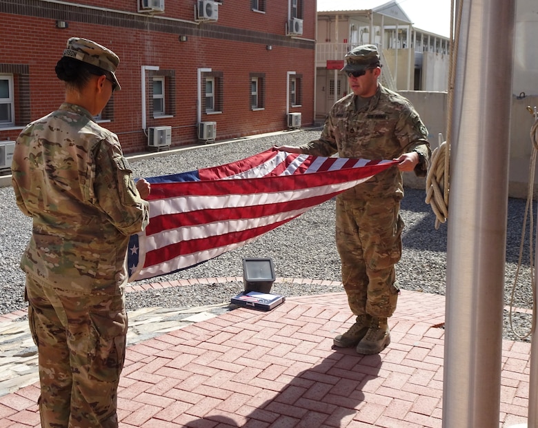 Lt. Col Malia Pearson, Kandahar Detachment Commander and Detachment Sergeant SFC Michael Pineda begin the formal folding process of the flag that was just raised and lowered at the Kandahar Resident Office on 9/11/18.
