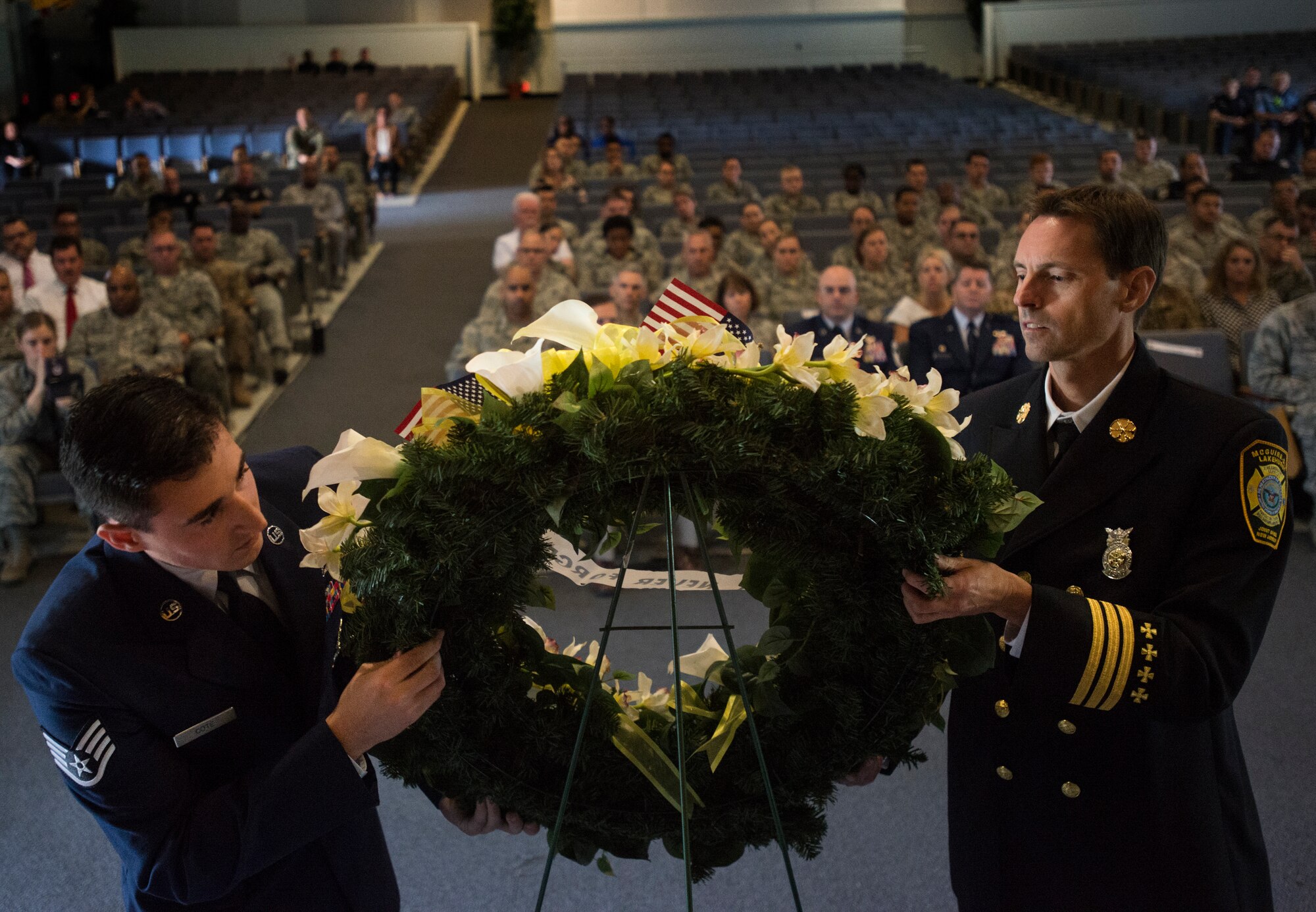 U.S. Air Force Staff Sgt. Christopher Cote and Chief Scott Staveley, 87th Civil Engineer Squadron fire fighters, lay a wreath of yellow flowers during a 9/11 memorial ceremony at the Timmermann Center on Joint Base McGuire-Dix-Lakehurst, N.J., Sept. 11, 2018. The ceremony paid special tribute to the victims and families of the attacks as well as the first responders and recovery teams who worked tirelessly around the clock in the wake of 9/11.