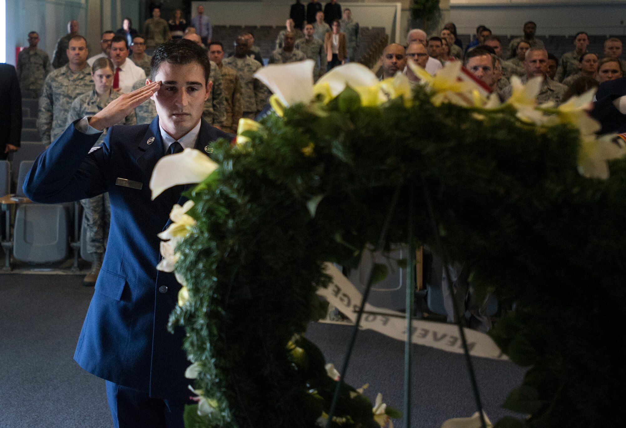 U.S. Air Force Staff Sgt. Christopher Cote, 87th Civil Engineer Squadron fire fighter, salutes a wreath of yellow flowers during a 9/11 memorial ceremony at the Timmermann Center on Joint Base McGuire-Dix-Lakehurst, N.J., Sept. 11, 2018. The ceremony paid special tribute to the victims and families of the attacks as well as the first responders who worked around the clock in the wake of 9/11.