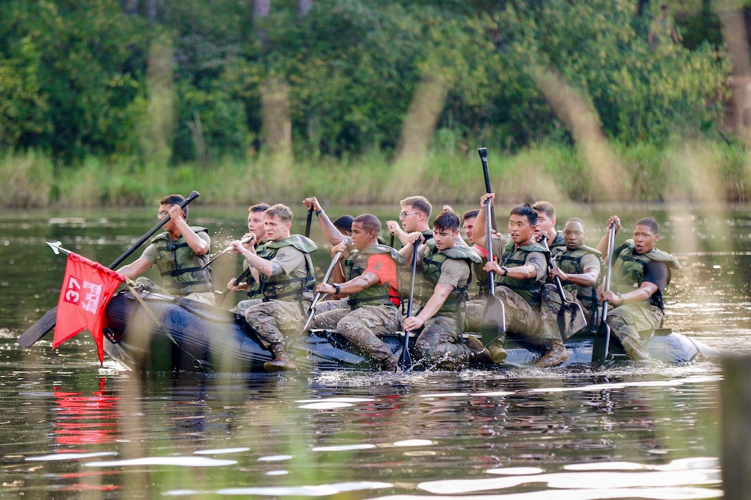 Soldiers row an inflatable boat.