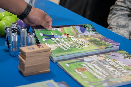 Frank Belton, a 773d Civil Engineer Squadron unit program coordinator, picks up literature designed to teach youth about the importance of being prepared during National Preparedness Month at Joint Base Elmendorf-Richardson, Alaska, Sept. 7, 2018. Emergency kits are essential to preparedness. They should be tailored to a geographical region and contain the basic essentials to survive for three days.