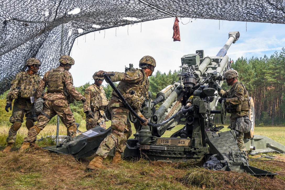 Soldiers load a howitzer.