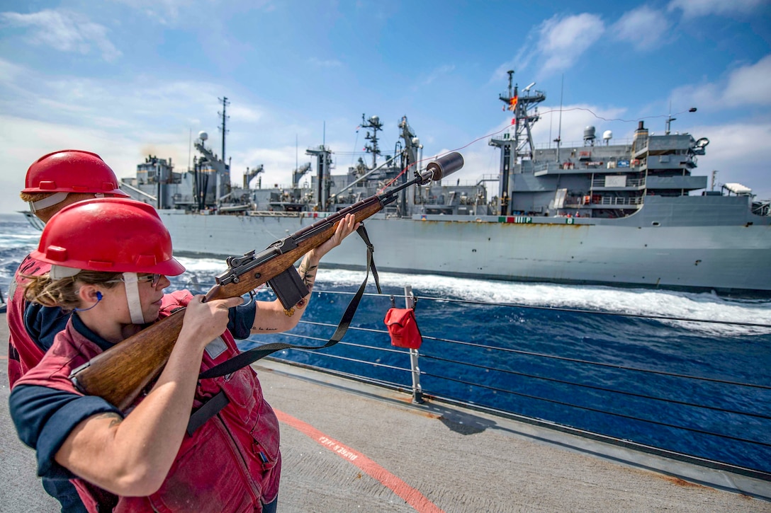 A sailor fires a shot line.