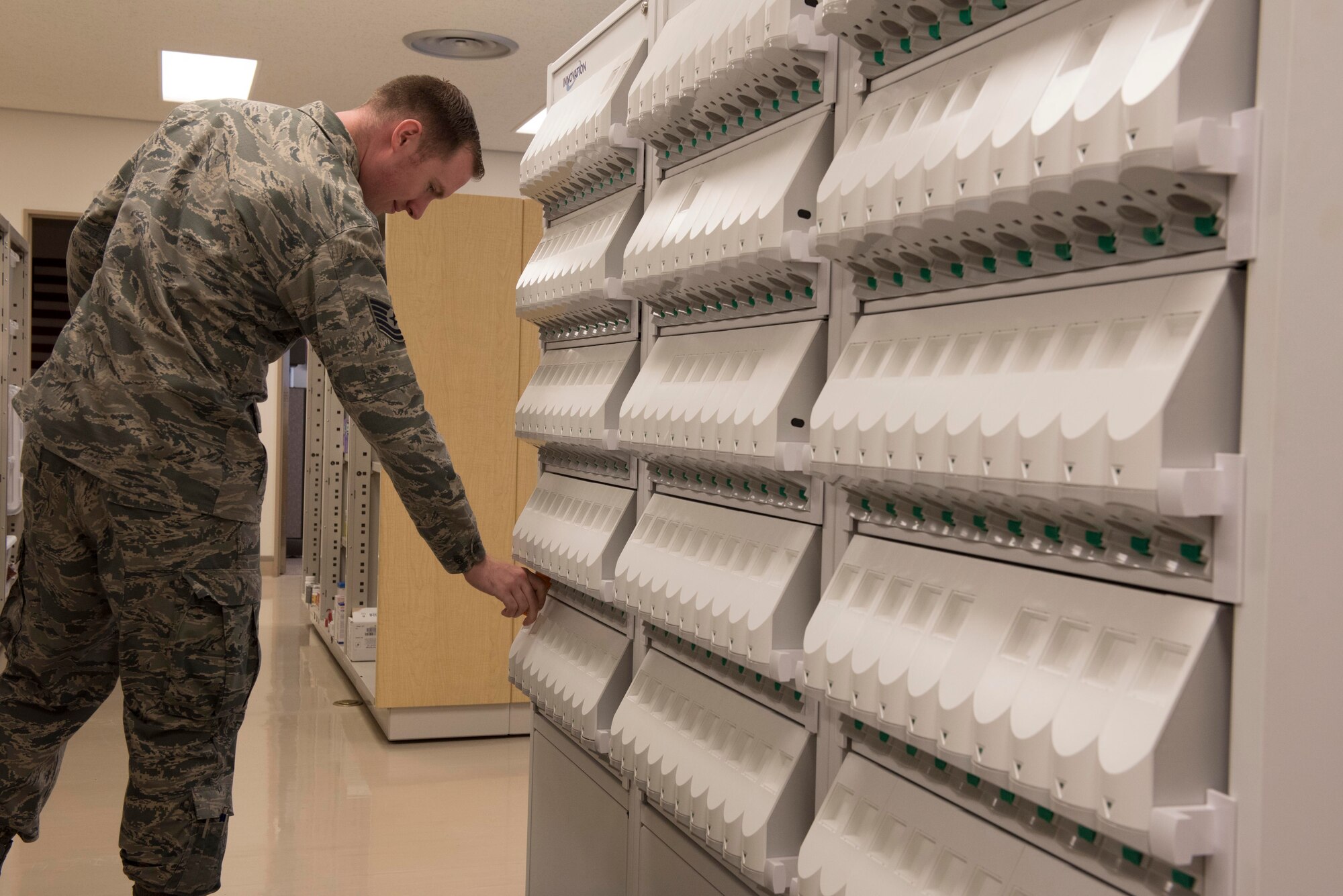 U.S. Air Force Tech. Sgt. Ryan Marr, 18th Medical Group pharmacy NCOIC, fills a prescription bottle from a pill-counting machine Sept. 10, 2018, at Kadena Air Base, Japan. Technicians use automated machines to count prescriptions involving large quantities of tablets to expedite their processes.